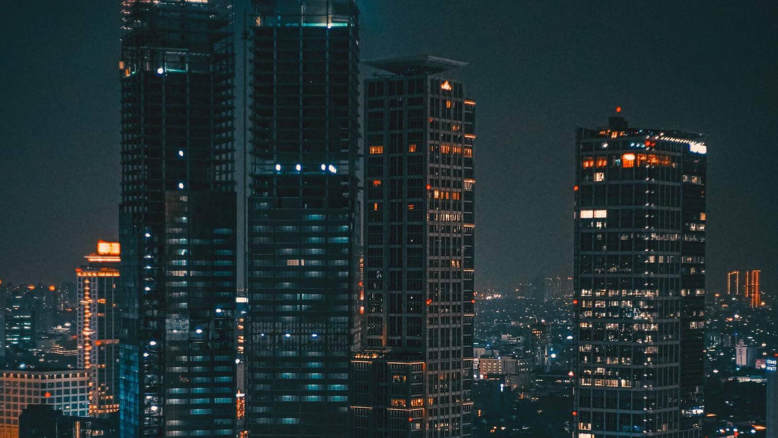 Gedung-gedung perkantoran kota di malam hari dengan lampu jendela menyala